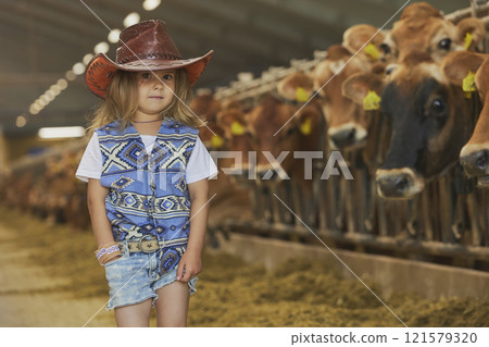 Charming child in a cowboy costume on a cows farm in Denmark Charming child in a cowboy costume on a cows farm in Denmark 121579320