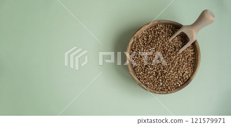 Raw buckwheat porridge in green background copy space. Whole spelt grain species. High protein fiber-rich vegan plant based food ingredient. Gluten free superfood healthy nutritional dietary 121579971