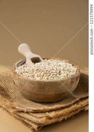 Pearl barley in neutral beige background. Whole spelt grain species. High protein fiber-rich vegan plant based food ingredient. Gluten free superfood healthy nutritional dietary alternative Pearl barley in neutral beige background. Whole spelt grain species. High protein fiber-rich vegan plant based food ingredient. Gluten free superfood healthy nutritional dietary alternative 121579994