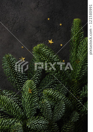 Close-up of fresh green pine branches with confetti in the shape of stars on dark textured background. A place for your text. 121580991
