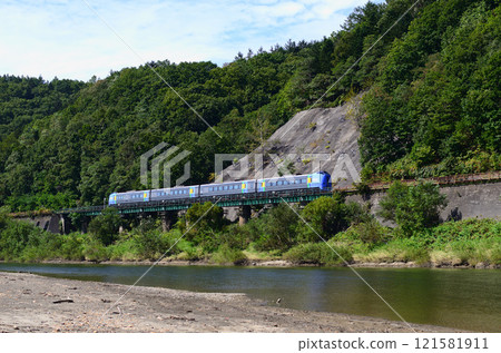 The Soya express train (following behind) passes through a narrow space between the hills and the Teshio River on an iron bridge. The Soya express train (following behind) passes through a narrow space between the hills and the Teshio River on an iron bridge. 121581911