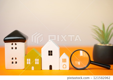 Magnifying glass and houses an orange background. House searching concept. Home appraisal. Property valuation. Choice of location for the construction. Search for housing, apartments. real estate 121582062