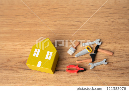 Miniature house and repair tools: pliers, saw, brushes, hammer. Concept of repair and maintenance of housing. 121582076