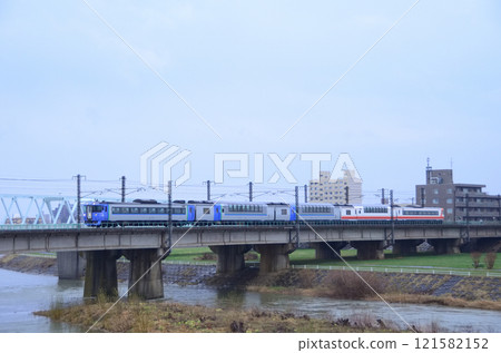 A chartered group train consisting of three high-decker green cars, including a car with a retro livery, crossing the Toyohira River Bridge in light rain 121582152