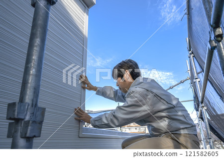 A male site supervisor working on renovating the exterior walls of a detached house A male site supervisor working on renovating the exterior walls of a detached house 121582605