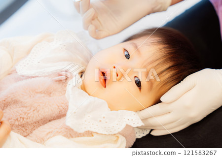 An anxious baby undergoing an infant checkup 121583267
