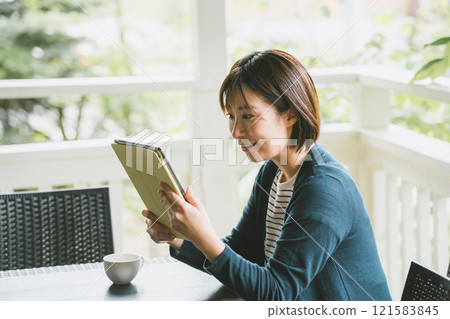 A woman looking at a tablet on the terrace A woman looking at a tablet on the terrace 121583845