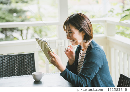 A woman looking at a tablet on the terrace A woman looking at a tablet on the terrace 121583846