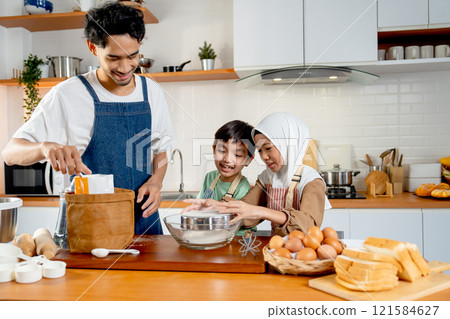 Asian father help his child to learn for cooking in the kitchen of their house with little muslim girl sift the flour into a bowl and they enjoy for the activity together. Asian father help his child to learn for cooking in the kitchen of their house with little muslim girl sift the flour into a bowl and they enjoy for the activity together. 121584627