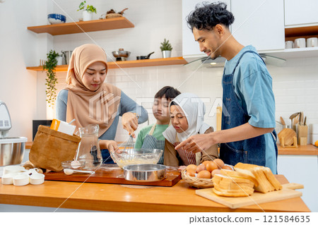 Front view of muslim mother show example to mix flour in the bowl for her child to make the bakery in kitchen of their house. Front view of muslim mother show example to mix flour in the bowl for her child to make the bakery in kitchen of their house. 121584635