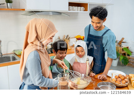 Muslim mother show example to mix flour in the bowl for her child to make the bakery in kitchen of their house. Muslim mother show example to mix flour in the bowl for her child to make the bakery in kitchen of their house. 121584639