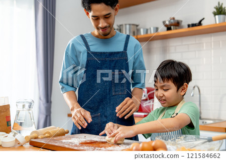 Asian father stand beside his son during teaching the boy to threshing flour for making bakery in kitchen of their house. Asian father stand beside his son during teaching the boy to threshing flour for making bakery in kitchen of their house. 121584662