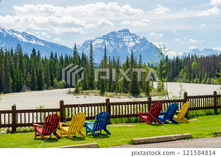 Jasper National Park summer landscape. Colorful adirondack chairs on Athabasca River bank. Alberta, Canada. Canadian Rockies. Mount Kerkeslin and Mount Hardisty in the background. 121584814