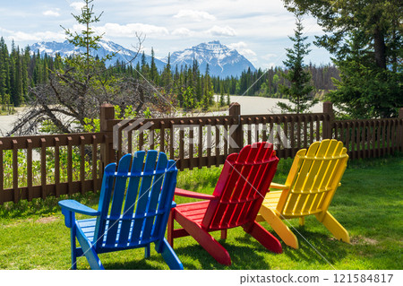 Jasper National Park summer landscape. Colorful adirondack chairs on Athabasca River bank. Alberta, Canada. Canadian Rockies. Mount Kerkeslin and Mount Hardisty in the background. 121584817