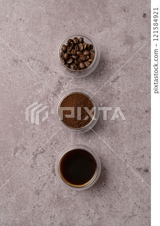 Top view fresh aromatic grain, ground and coffee drink in a small glasses, gray concrete. Copy space background, cover, backdrop, texture. Place for adding text or design Top view fresh aromatic grain, ground and coffee drink in a small glasses, gray concrete. Copy space background, cover, backdrop, texture. Place for adding text or design 121584921