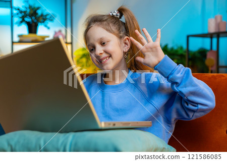 Preteen child girl looking at laptop camera, making video webcam conference call with friends family 121586085