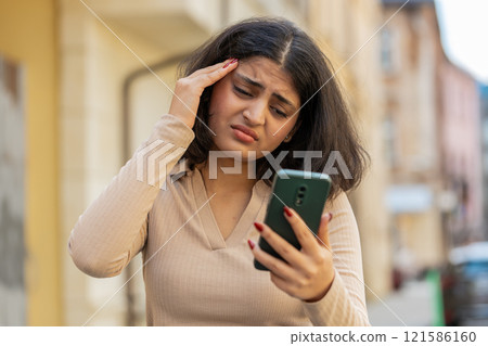 Indian woman use smartphone loses receive bad message mail news loss fail outdoors on city street 121586160