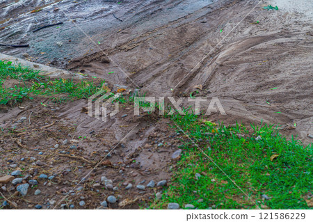 Traces of mud flows of earth washed away from green areas of park to the surface of asphalt in the process of sudden flooding with huge amount of water due to a downpour or burst water pipe Traces of mud flows of earth washed away from green areas of park to the surface of asphalt in the process of sudden flooding with huge amount of water due to a downpour or burst water pipe 121586229