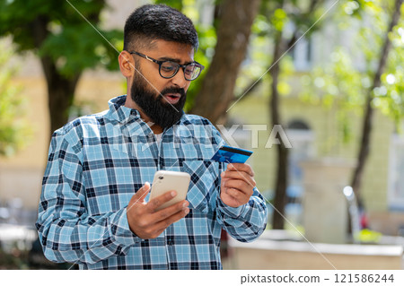 Shocked man trying to pay online shopping with smartphone blocked credit card lack of money balance Shocked man trying to pay online shopping with smartphone blocked credit card lack of money balance 121586244