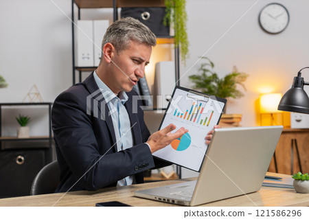 Confident young freelancer shows graphical analytics during video call on laptop at office desk Confident young freelancer shows graphical analytics during video call on laptop at office desk 121586296