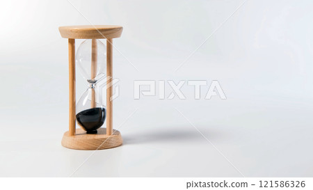 Hand tilting an hourglass as sand flows between chambers, representing time passing Hand tilting an hourglass as sand flows between chambers, representing time passing 121586326