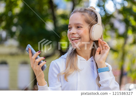 Young woman tourist listening to music using wireless headphones and smartphone on city street Young woman tourist listening to music using wireless headphones and smartphone on city street 121586327