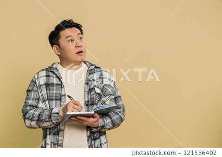 Asian man making notes writing thoughts with pen into notepad notebook diary to do list good idea Asian man making notes writing thoughts with pen into notepad notebook diary to do list good idea 121586402