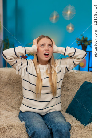 Caucasian woman irritated by noisy neighbors covering ears on sofa construction music loud indoors 121586414