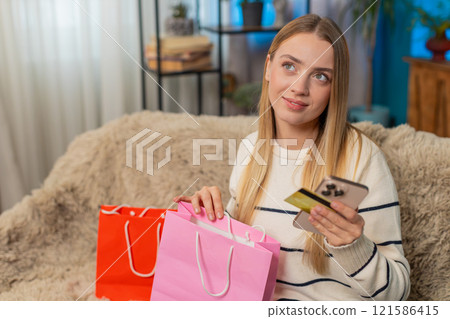 Caucasian woman happy online purchase on sofa using mobile phone gold credit card smiling indoors 121586415