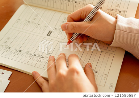 Close-up of a young foreign woman's hands writing and studying kanji to master the Japanese language 121586687