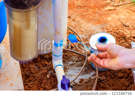 Plumber inspects, maintains water well system in environment, ensuring proper water line installation Plumber inspects, maintains water well system in environment, ensuring proper water line installation 121586756