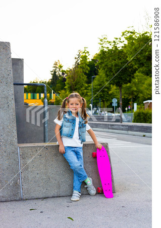 Cute little girl stands with a skateboard 121586908
