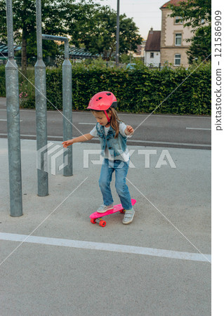 cute girl in a pink helmet rides a skateboard 121586909