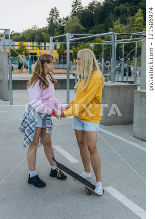 young mother with her daughter riding a skateboard in the park. mother with teenager young mother with her daughter riding a skateboard in the park. mother with teenager 121586974