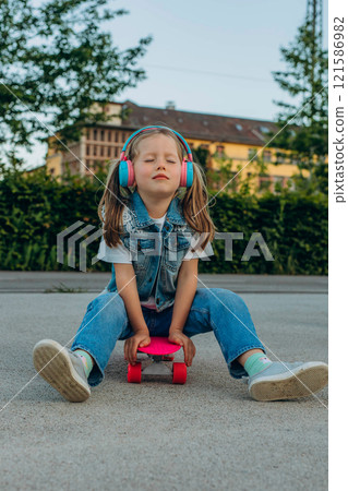 kid girl playing surf skate or skateboard in headphones kid girl playing surf skate or skateboard in headphones 121586982