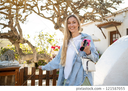Happy woman holding smartphone by wooden railing 121587055