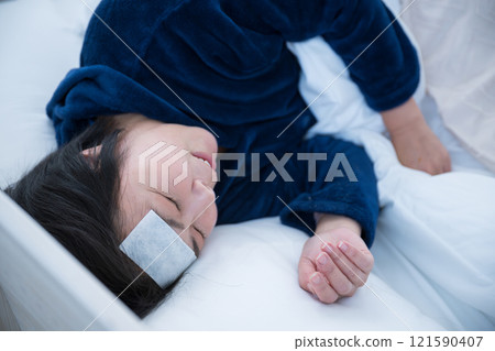 A bird's-eye view of a middle-aged woman who has caught a cold and is in bed, cooling her head, saying, "Oh, I've got a fever." 121590407