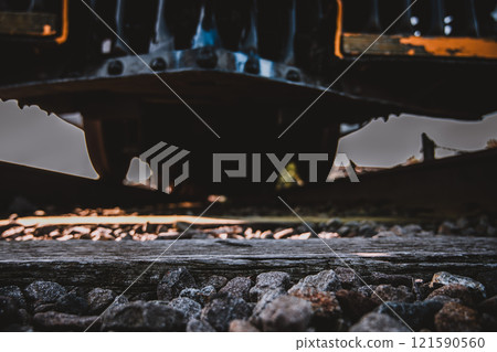 Track level view of a railroad train and wheels as they cross over 121590560