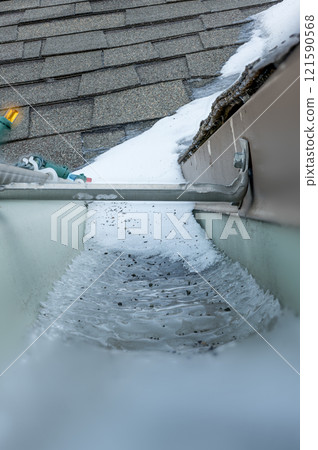 Ice and snow building up inside a rooftop gutter system on a residential house 121590568