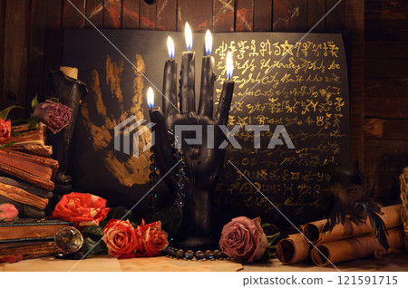 Mystic still life with magic spell book, roses and burning black candles on old altar table. Occult, esoteric, wicca, Halloween and gothic concept. No foreign language, all symbols are fictional. 121591715