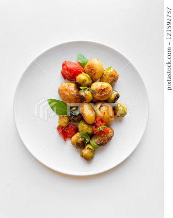 Overhead view of plate with roasted baby potatoes, Brussels sprouts, and cherry tomatoes garnished with fresh basil, clean eating concept with copy space. Overhead view of plate with roasted baby potatoes, Brussels sprouts, and cherry tomatoes garnished with fresh basil, clean eating concept with copy space. 121592737