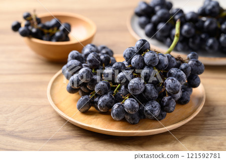 Black grapes on wooden plate, Seedless grapes 121592781