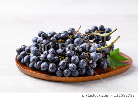 Black grapes on wooden plate with white table, Seedless grapes 121592782
