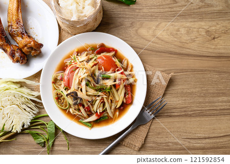 Spicy papaya salad (Som Tum) eating with sticky rice and grilled chicken wing, Local Thai food 121592854