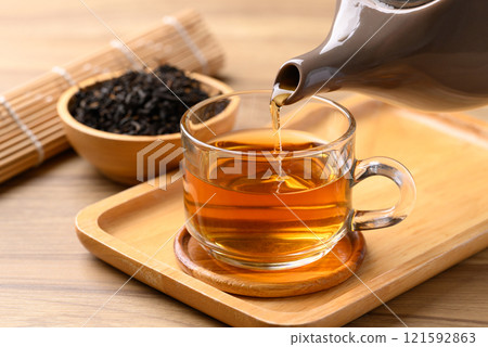 Black tea in cup glass with teapot pouring tea, Healthy herbal drink Black tea in cup glass with teapot pouring tea, Healthy herbal drink 121592863