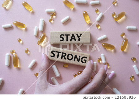 Stay Strong symbol. Concept word Stay Strong on wooden blocks. Beautiful pink background with pills. Doctor Hand. Medicine and Stay Strong concept. Copy space Stay Strong symbol. Concept word Stay Strong on wooden blocks. Beautiful pink background with pills. Doctor Hand. Medicine and Stay Strong concept. Copy space 121593920