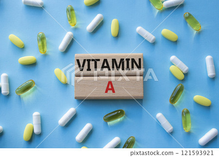 Vitamin A symbol. Concept word Vitamin A on wooden blocks. Beautiful blue background with pills. Medicine and Vitamin A concept. Copy space Vitamin A symbol. Concept word Vitamin A on wooden blocks. Beautiful blue background with pills. Medicine and Vitamin A concept. Copy space 121593921