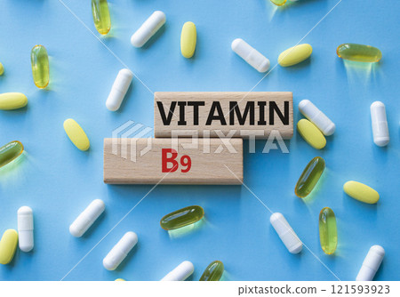 Vitamin B9 symbol. Concept word Vitamin B9 on wooden blocks. Beautiful blue background with pills. Medicine and Vitamin B9 concept. Copy space Vitamin B9 symbol. Concept word Vitamin B9 on wooden blocks. Beautiful blue background with pills. Medicine and Vitamin B9 concept. Copy space 121593923