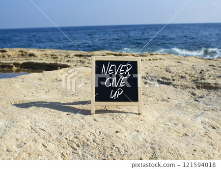 Never give up symbol. Blackboard with Concept words Never give up. Beautiful sea background. Business and Never give up concept. Copy space. Never give up symbol. Blackboard with Concept words Never give up. Beautiful sea background. Business and Never give up concept. Copy space. 121594018