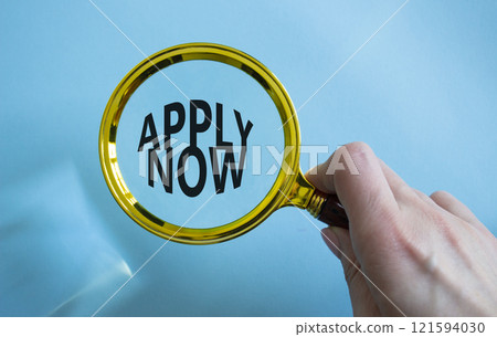 Apply now symbol. Magnifying Glass with Concept word Apply now. Beautiful blue background. Businessman hand. Business and Apply now concept. Copy space 121594030